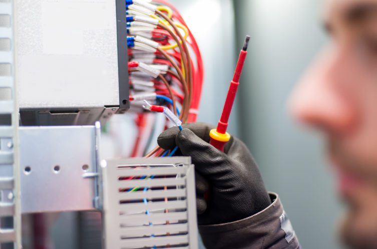Closeup of electrician engineer works with electric cable wires of fuse switch box. Electrical equipment.