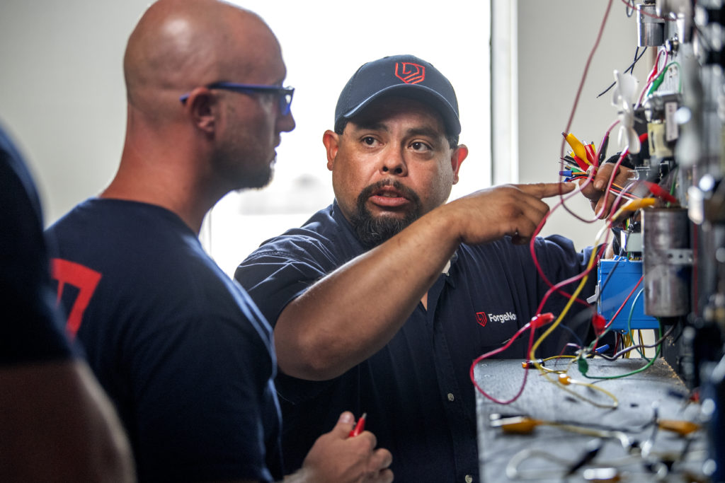 A ForgeNow instructor demonstrating a technique on an electrical panel for a student.